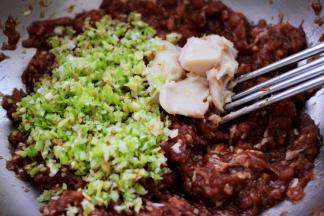 把搅拌好的葱姜和猪油放入猪肉馅里