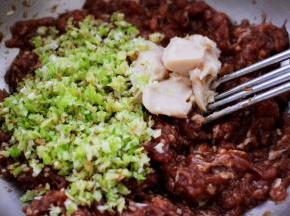 把搅拌好的葱姜和猪油放入猪肉馅里