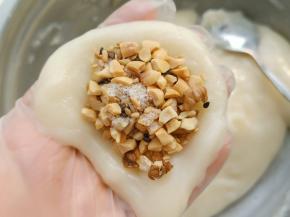 戴上一次性手套，取30克糯米面团，用手按扁放入适量的馅包起来。