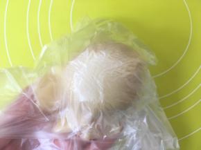 揭掉一层保鲜袋，放上莲蓉蛋黄馅，之后倒扣在手上，揭掉保鲜袋，收好收口；
