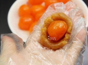 取一小团莲蓉压扁，放一个咸蛋黄，包裹起来，莲蓉蛋黄馅就做好了。