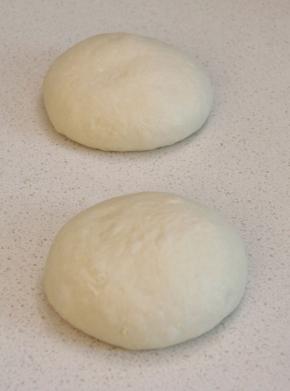 冷藏好的面团拿出微排气，分割成2等份，适当滚圆后盖好静置40分钟回温。（此时烤箱进行预热，COUSS CO-960S电烤箱，间隔放入双层卡士烘焙石板，设置300度，预热40分钟以上）。