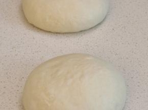 冷藏好的面团拿出微排气，分割成2等份，适当滚圆后盖好静置40分钟回温。（此时烤箱进行预热，COUSS CO-960S电烤箱，间隔放入双层卡士烘焙石板，设置300度，预热40分钟以上）。