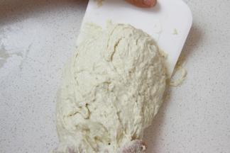 台面撒较多干粉，取出面团，借助刮板将其适当收圆。