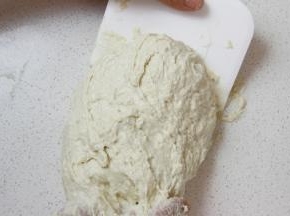 台面撒较多干粉，取出面团，借助刮板将其适当收圆。