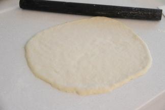 台上撒适量干粉防粘，将面团整理成薄薄的圆饼状。