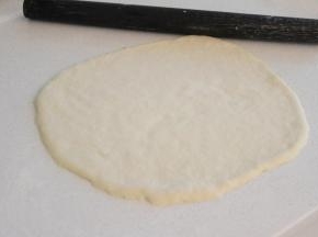 台上撒适量干粉防粘，将面团整理成薄薄的圆饼状。