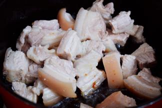 放入五花肉，翻炒至上糖色