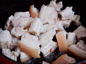 放入五花肉，翻炒至上糖色