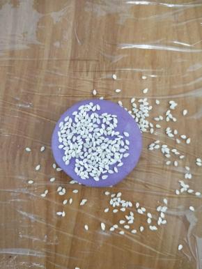 把刚才搓圆的糯米团用手轻轻压一下，再放到芝麻里，沾满芝麻。