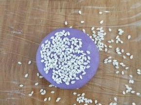 把刚才搓圆的糯米团用手轻轻压一下，再放到芝麻里，沾满芝麻。