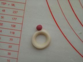 适量红色面团揉一个小圆，粘到指环上面