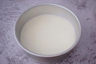 把模具从冰箱取出来，先把白色慕斯糊倒入并轻轻拿起模具慢慢摇一摇，使慕斯均匀的分布于整个底部