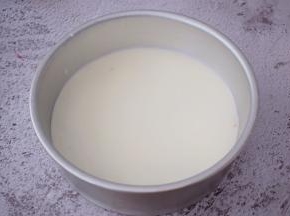 把模具从冰箱取出来，先把白色慕斯糊倒入并轻轻拿起模具慢慢摇一摇，使慕斯均匀的分布于整个底部