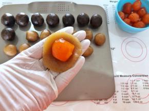 5、取一个莲蓉月饼馅按扁，放入一个咸蛋黄。