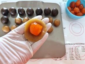 5、取一个莲蓉月饼馅按扁，放入一个咸蛋黄。