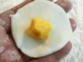 揪一块面团，捏薄，放入流心陷，包起来。