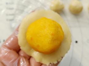 取一份月饼皮放在手心按扁，放入冻好的馅包起来，收口收好。