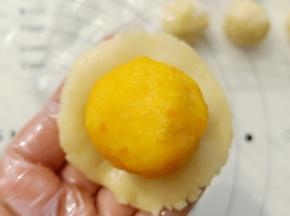 取一份月饼皮放在手心按扁，放入冻好的馅包起来，收口收好。