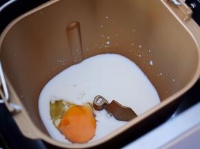 然后在面包桶的一角打入一个鸡蛋