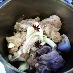 将猪骨用温水洗净，放入电压力锅里，将葱姜、八角和调料包放入。