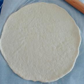 取一份面团，底下垫一张油纸，擀平。 