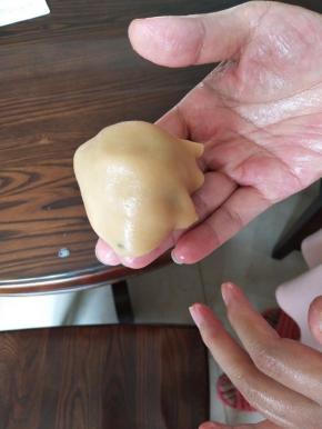 压好的圆饼，放上五仁馅，然后倒扣过来，像蘑菇是的，轻轻按压，慢慢包住五仁馅