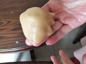 压好的圆饼，放上五仁馅，然后倒扣过来，像蘑菇是的，轻轻按压，慢慢包住五仁馅