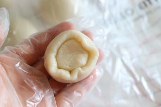 取一个油皮擀开，包入油酥，这个方法是用手虎口的位置推着收口，然后收口向下放置。