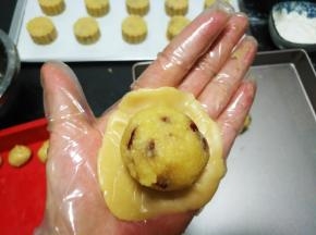 取一份饼皮，放入左手掌心，用右手的三个手指轻柔的按压面团，压成小圆饼状，.放入一个馅