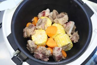 玉米切成四小段，胡萝卜滚刀切块，和排骨一起放入炒菜锅内