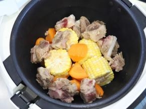 玉米切成四小段，胡萝卜滚刀切块，和排骨一起放入炒菜锅内