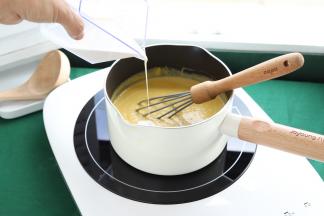 将南瓜浓汁倒入奶锅内，再倒入淡奶油，电磁炉中小火加热