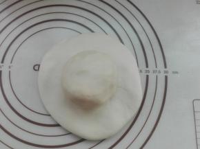 将醒发好的水油皮面团直接按扁成圆形，放入前面制作好的油酥面团