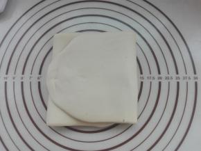 再次将其擀成长方形，同样再次进行三折，盖好保鲜膜继续醒发10分钟