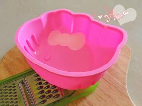 准备好硅胶模具，由于蝴蝶结部分是斜的，要先用东西垫高，使蝴蝶结尽量水平状态。
将粉色慕斯糊挤到蝴蝶结的位置，填满之后放入冰箱，冷藏至凝固。