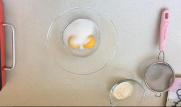 馅料部分需要冷藏，所以先来制作馅料。将馅料部分里的白砂糖，其中的一半倒入到蛋黄中