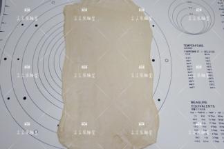 将面团旋转90度，再次擀开擀薄。
