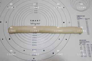 由左侧像右侧卷起来，然后在案板上滚动几下，滚成粗细相同的长条。