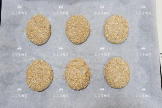 将白芝麻倒入平盘中，将包好的酥饼表面均匀的粘上白芝麻，全部做好放入烤盘。