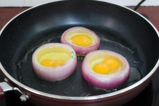翻转洋葱之后，把鸡蛋打入洋葱圈里，让鸡蛋完全在洋葱里面。不要移动洋葱，容易漏出蛋液。瞧，这是双蛋黄的鸡蛋，漂亮吧。