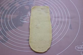 取一块松弛好的面团，用擀面杖擀成长舌状。