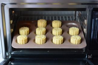 包完饼皮的月饼，放入冰箱冷冻一个小时以上进行烘烤。烤箱预热230度，冻硬的月饼表面喷上一些水，放入烤箱，烘烤5分钟定型