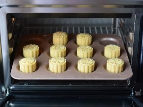 包完饼皮的月饼，放入冰箱冷冻一个小时以上进行烘烤。烤箱预热230度，冻硬的月饼表面喷上一些水，放入烤箱，烘烤5分钟定型