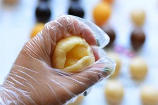 把面团压成圆饼状，中间放上做好的奶黄馅，让馅料紧贴着饼皮，用虎口慢慢的从下往上推饼皮，让饼皮贴着奶黄馅慢慢的往上收，最后收口滚圆，依次把所有的月饼做成圆球状备用