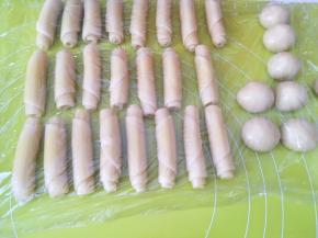 之后从长条的一头卷起来，将面团卷成牛舌卷状，继续盖保鲜膜