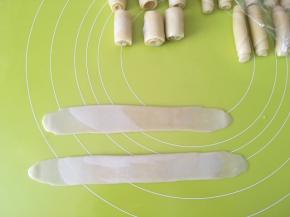 全部擀好后，再拿起最先做好的两个牛舌卷，再次擀成长条，之后卷起来，盖保鲜膜