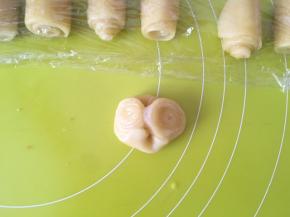 取一个牛舌卷，用手指在中间压一下，之后用擀面杖擀成圆片 