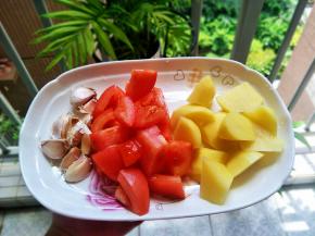 西红柿洗干净切小块，蒜头剥一个个出来，土豆去皮切小块，鸡翅中洗干净，用厨房纸擦干水分，在面前划几刀，方便入味