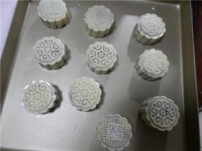 在金盘上压出花纹（金盘防粘），月饼表面喷层水防裂。